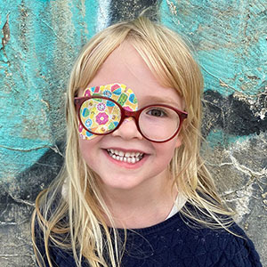 Glad pige med briller og ortopad øjenplaster.. En af mange brillebørn.