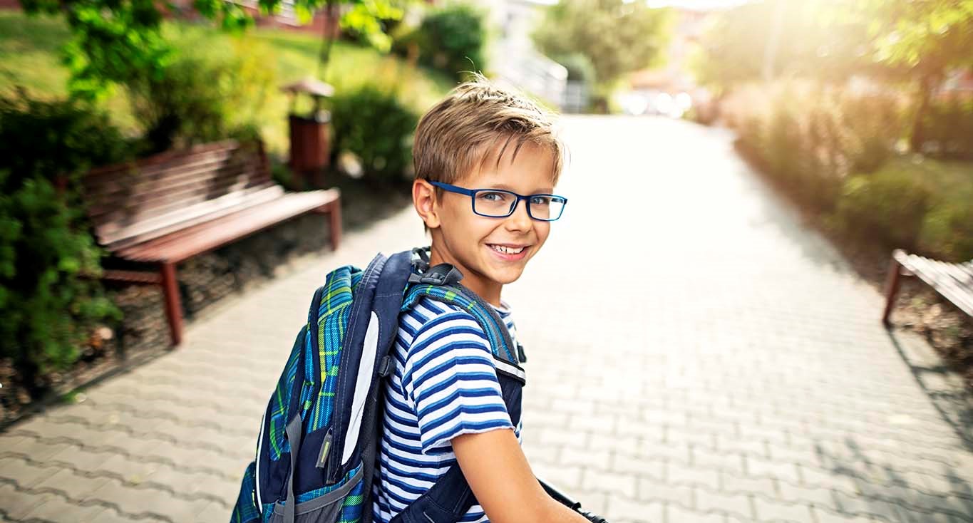 Smilende dreng med blå briller. Tilskud til briller til børn.